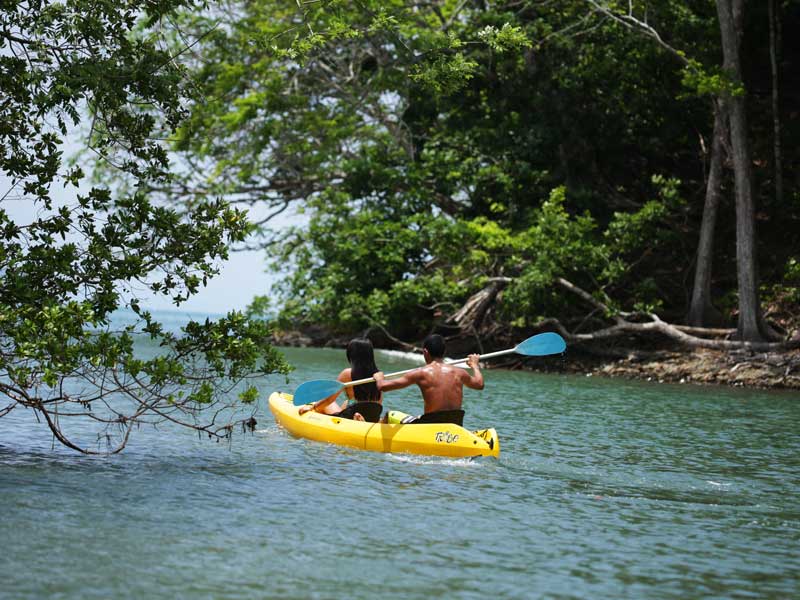 Um homem está a remar um caiaque na água.