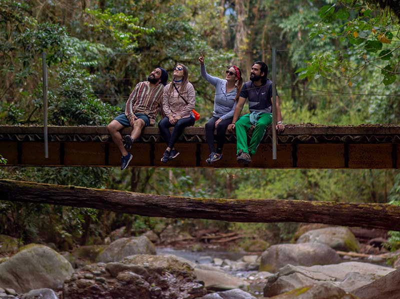Um grupo de pessoas sentadas numa ponte sobre um rio.