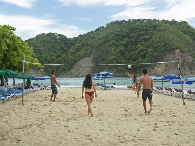 Um grupo de pessoas a jogar voleibol numa praia.