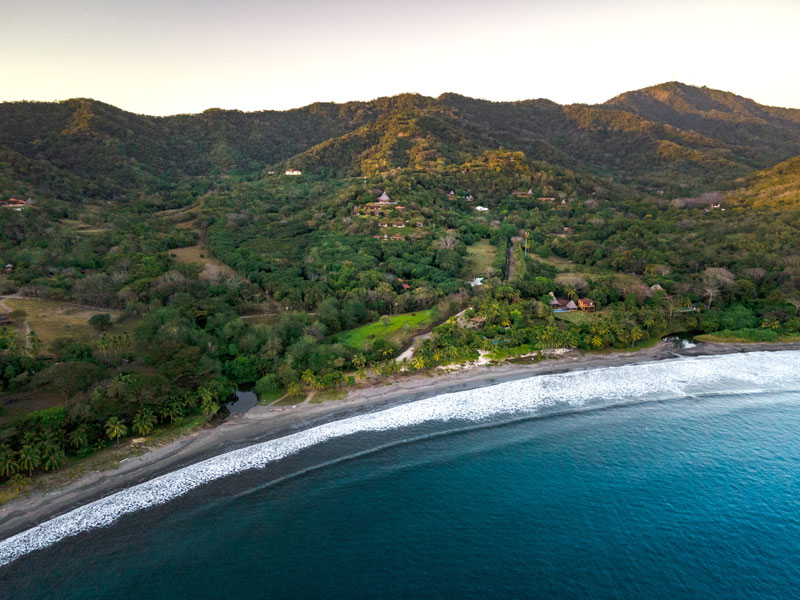 Uma vista aérea de uma praia e de montanhas.