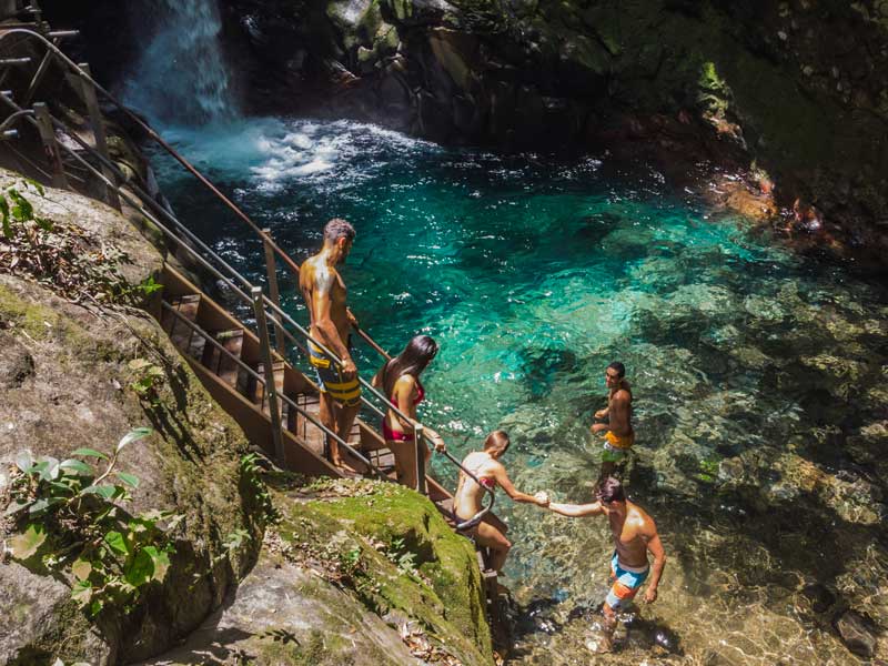 Um grupo de pessoas no topo de um penhasco junto a uma cascata.
