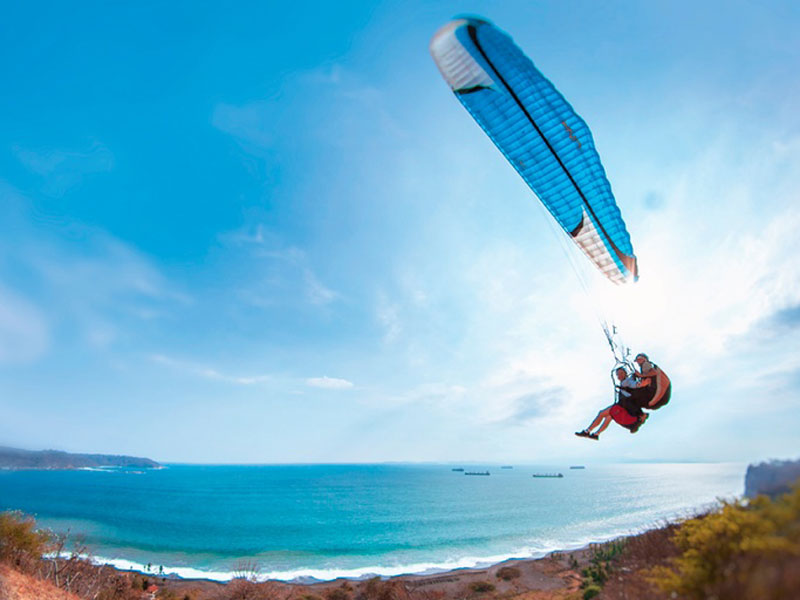 Um homem a voar pelo ar enquanto anda de kiteboard