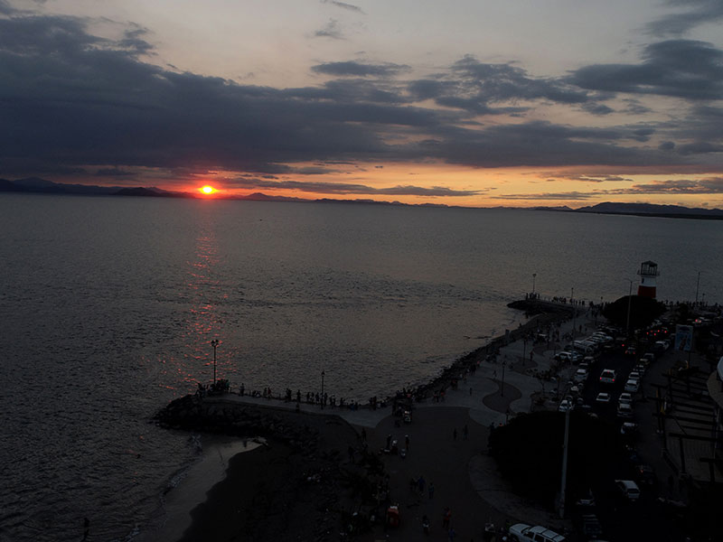 Uma grande massa de água com um pôr do sol em pano de fundo.