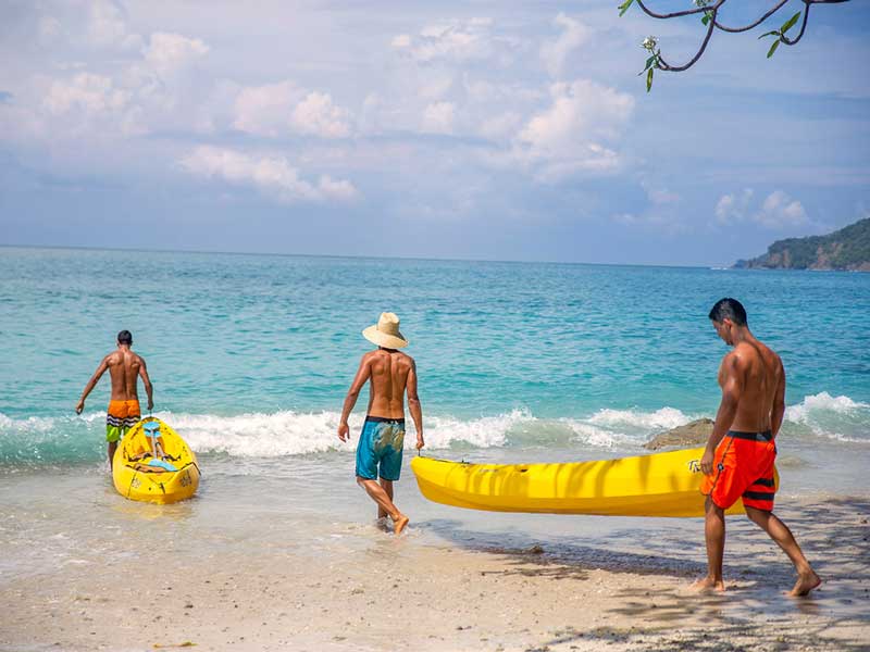 Um grupo de pessoas numa praia com uma prancha de surf amarela.