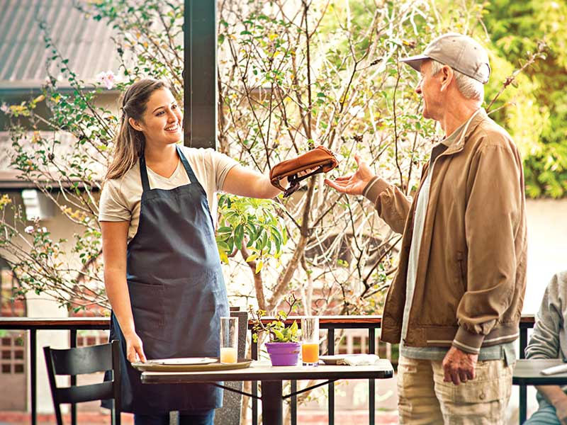 Um homem a entregar um tabuleiro de comida a uma mulher.