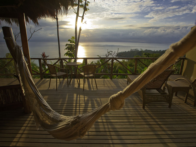 Uma cama de rede num deck com vista para o oceano.