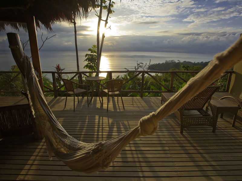 Uma cama de rede num deck com vista para o oceano.