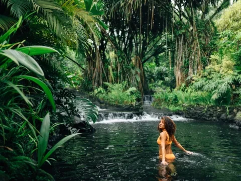 Mulher a caminhar numa nascente na selva