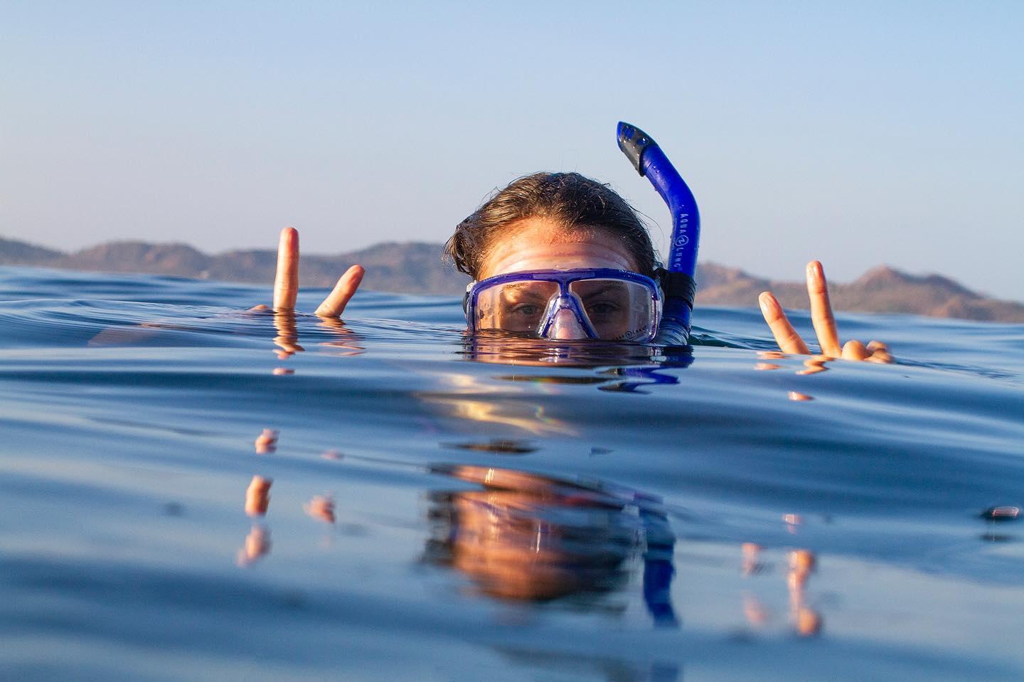 mulher com sinais de paz a fazer snorkeling