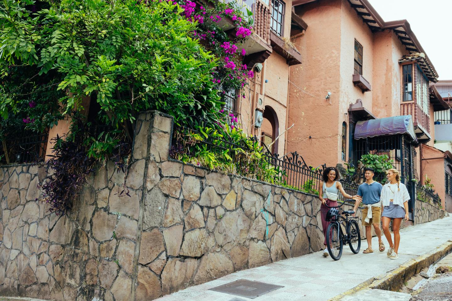 amigos a passear num bairro com uma bicicleta