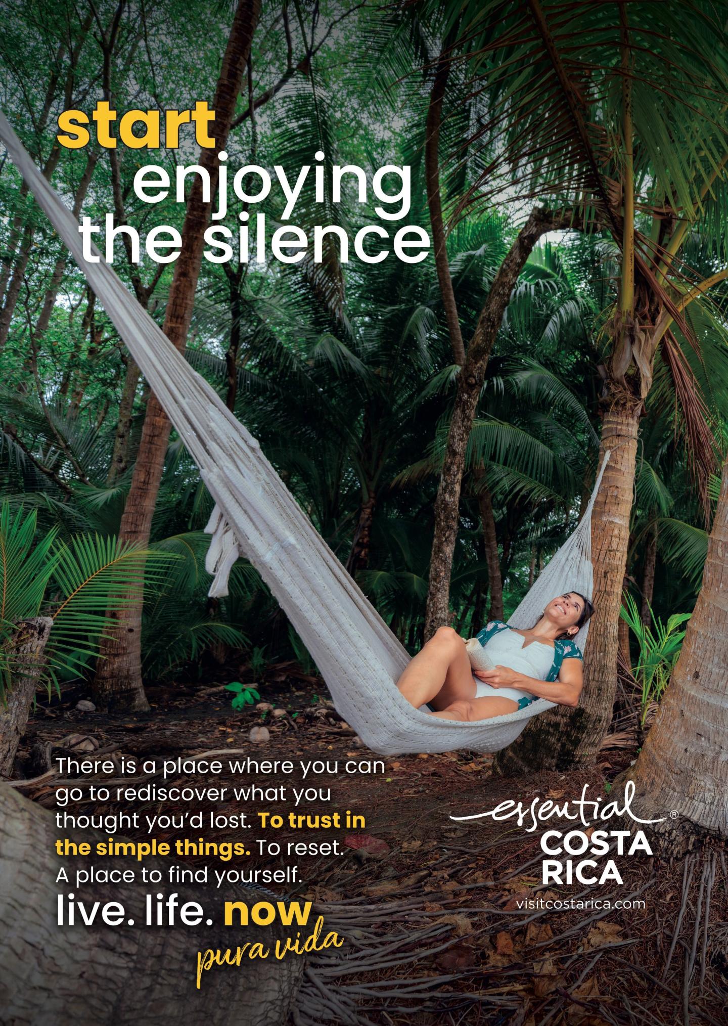 Anúncio que mostra uma mulher a relaxar numa rede entre palmeiras num cenário tropical. Título: «Comece a desfrutar do silêncio». Marca: «esencial Costa Rica, visitcostarica.com.